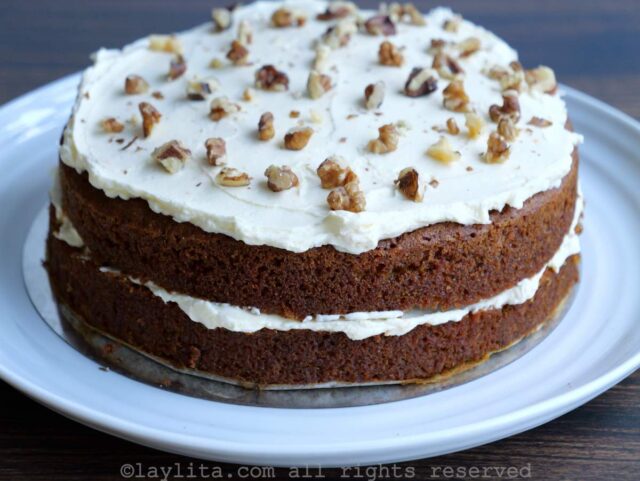 Two layers of cake with cream cheese frosting and nuts