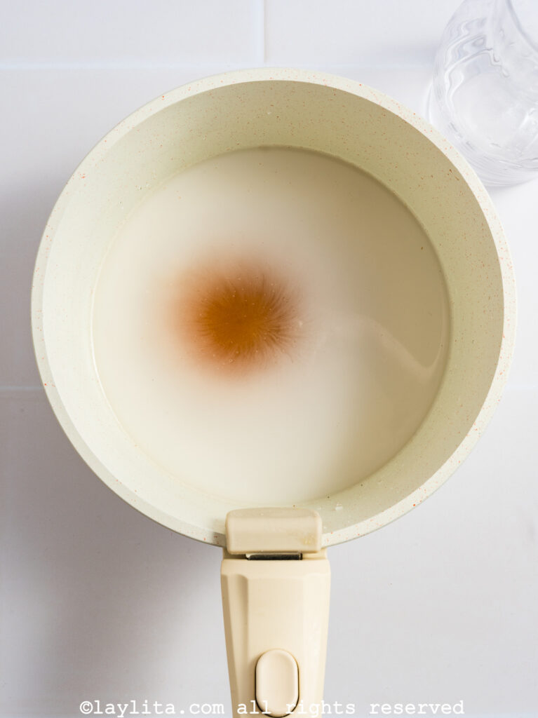 A white pot full of water, cornstarch, brown sugar and salt