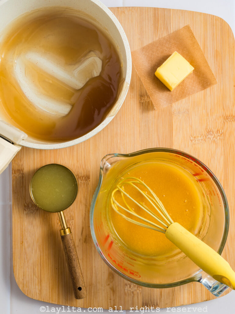 A bowl with beaten egg yolks nest to a pot with hot cornstarch sugar mix
