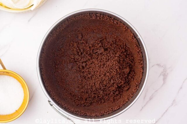 A round baking mold with a chocolate cookie crust in it
