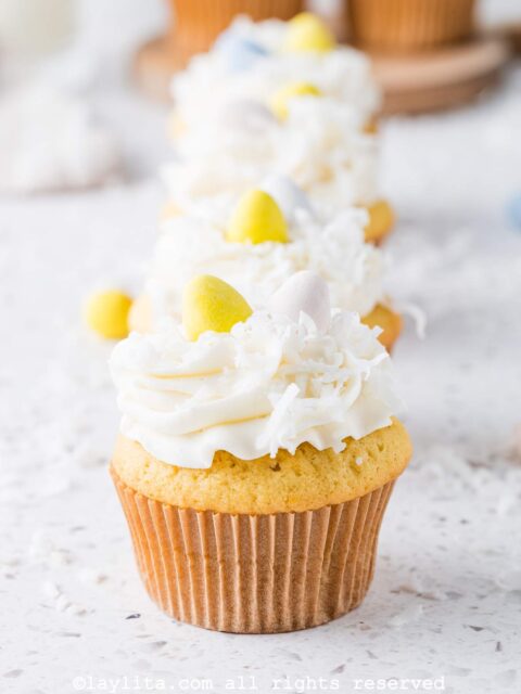 Decorating the coconut cupcakes with coconut buttercream frosting, coconut flakes and easter egg candies