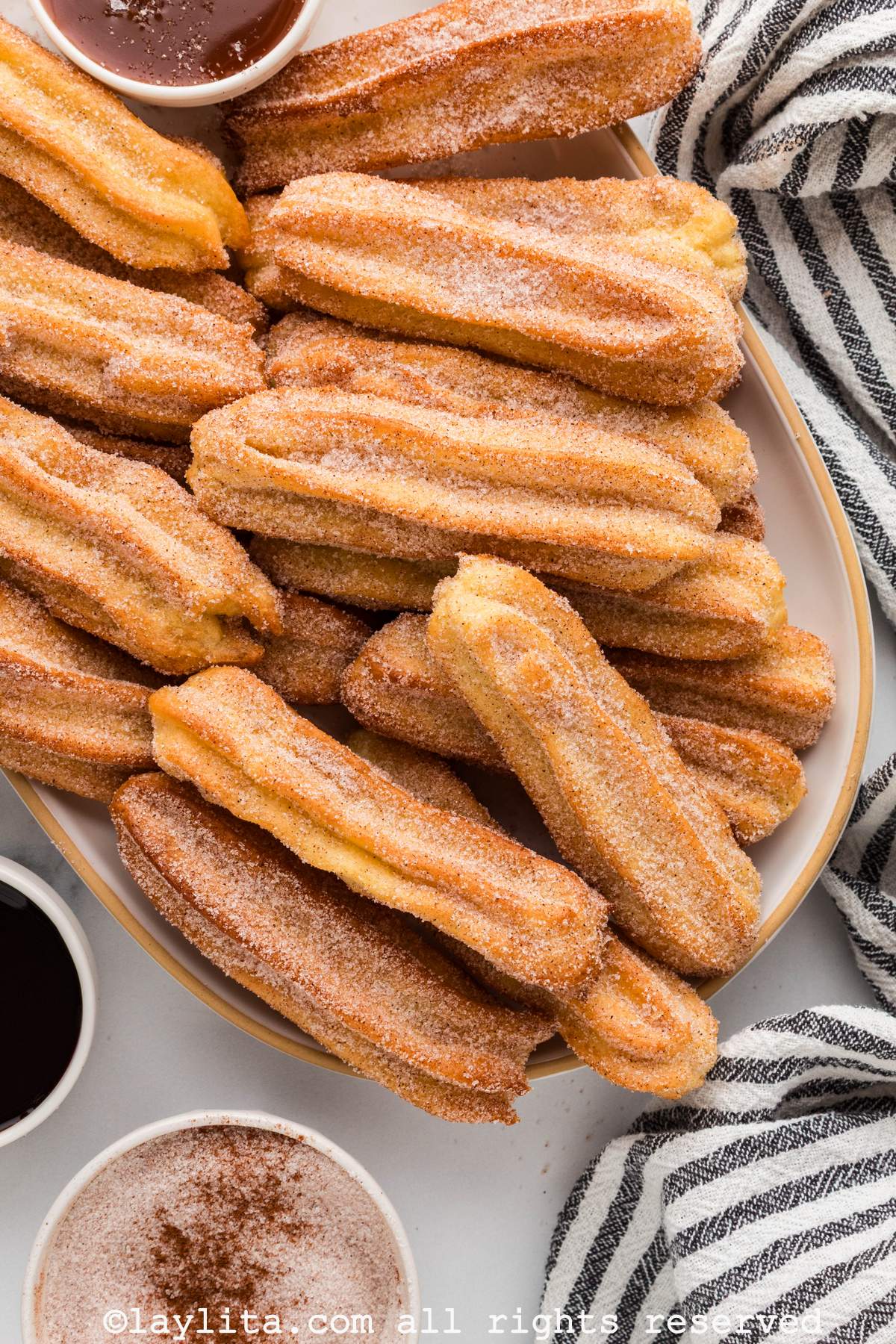 Overhead shot of a tray of churros next to a striped kitchen towel