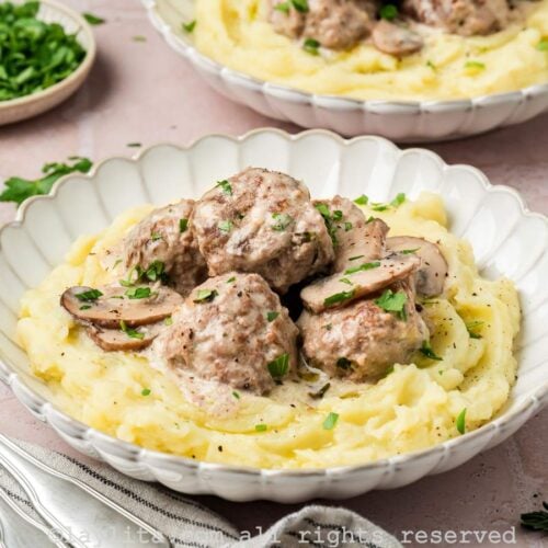 Beef stroganoff meatballs served in a bowl with mashed potatoes.