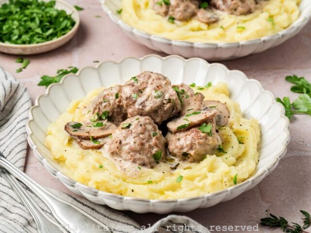 Beef stroganoff meatballs served in a bowl with mashed potatoes.