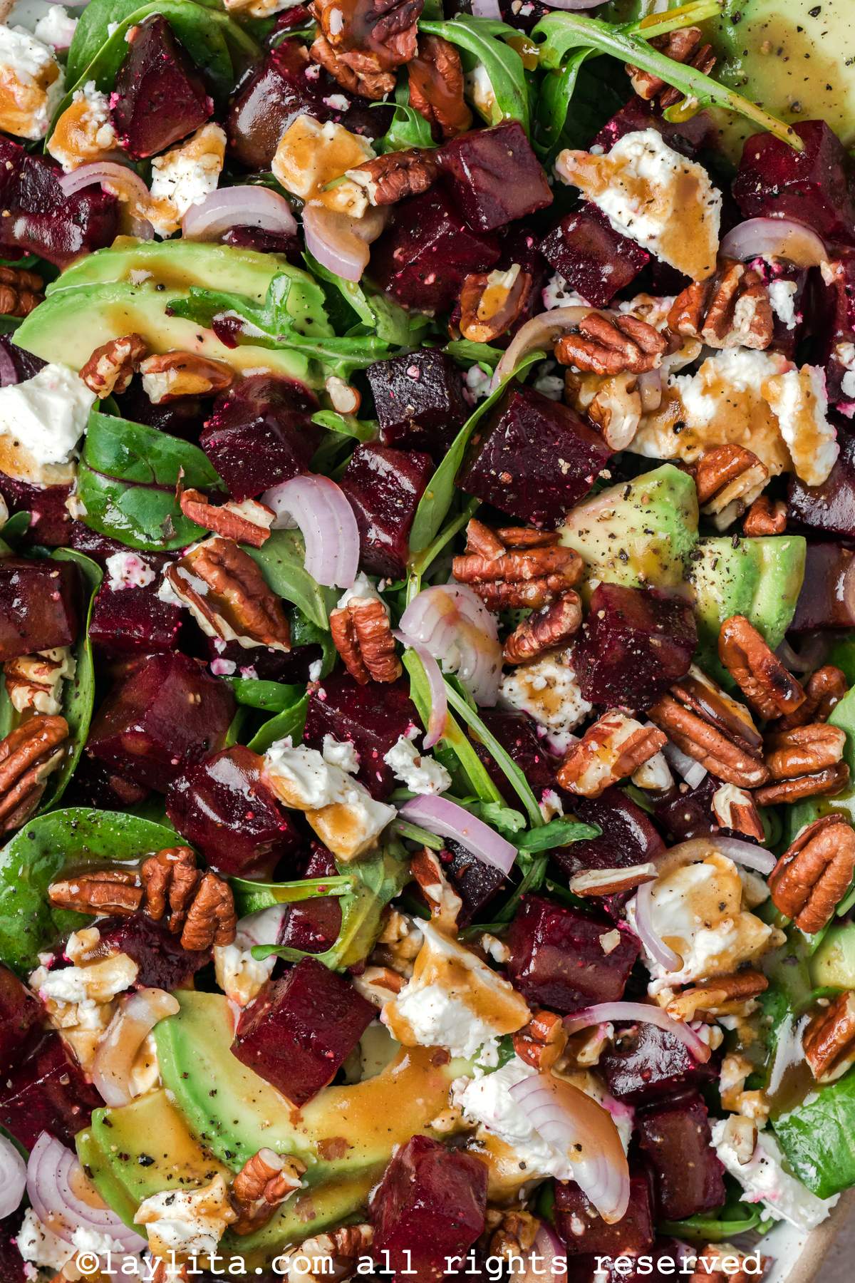 Close up of a beet salad with feta cheese, pecans, shallots and avocado slices