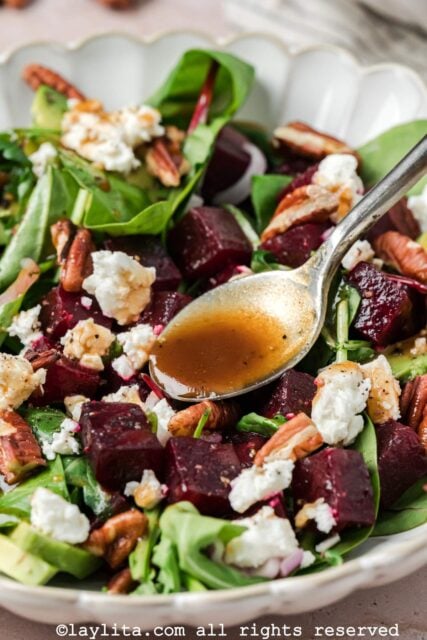 Spooning the balsamic dressing onto the beet salad in a bowl