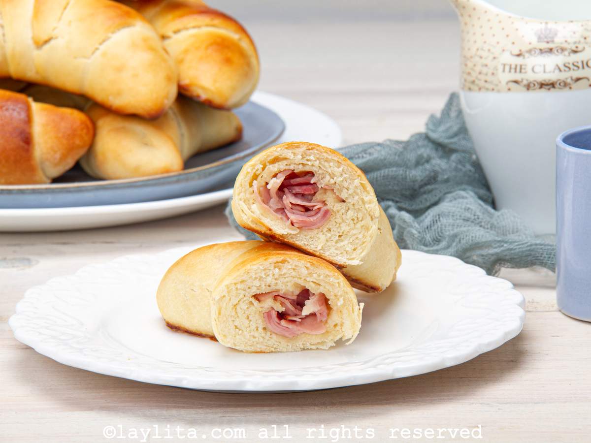 A Venezuelan ham cachito bread roll cut in half with the halves leaning on each other to show the ham filling
