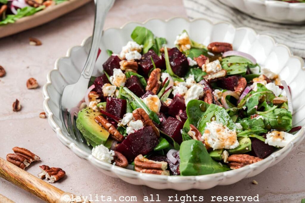 Roasted beet salad with feta served in a salad bowl with the platter of salad in the background.