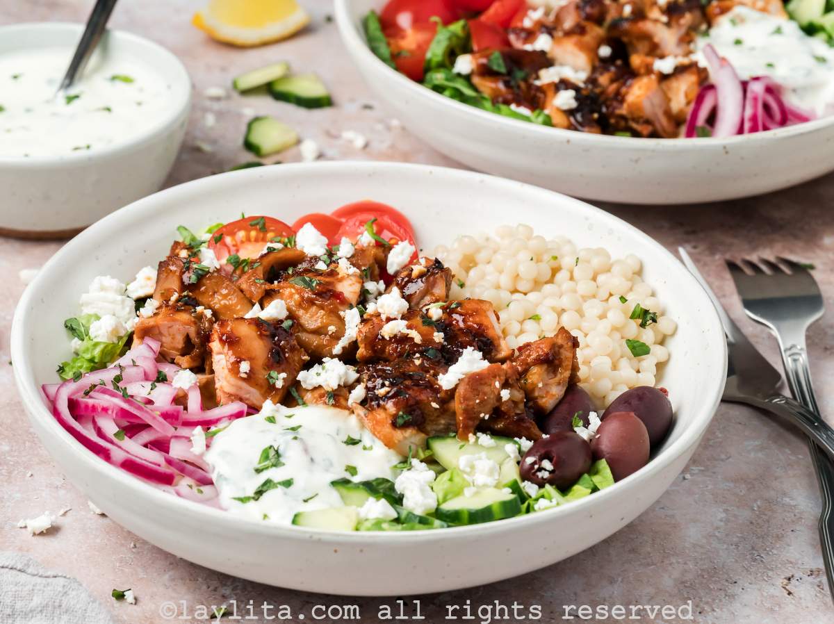 Side view of two harissa chicken bowls, both with toppings and mint yogurt sauce on top.