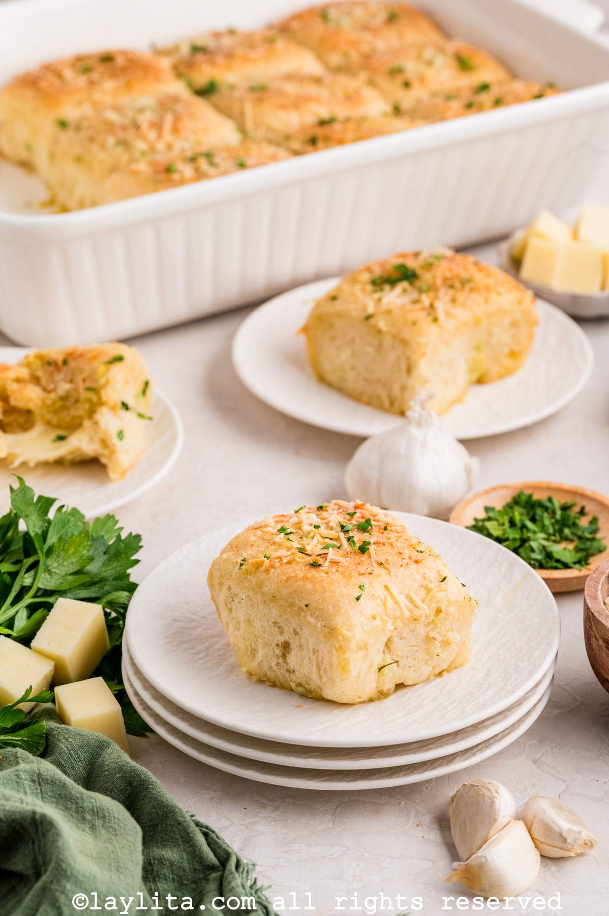 Dinner roll served on a plate with more rolls in the baking dish in the background.