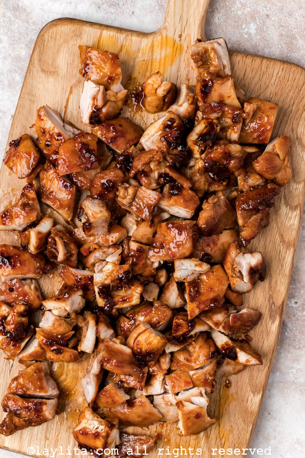 Overhead view of honey harissa marinated chicken thighs cut into bite sized pieces on a cutting board