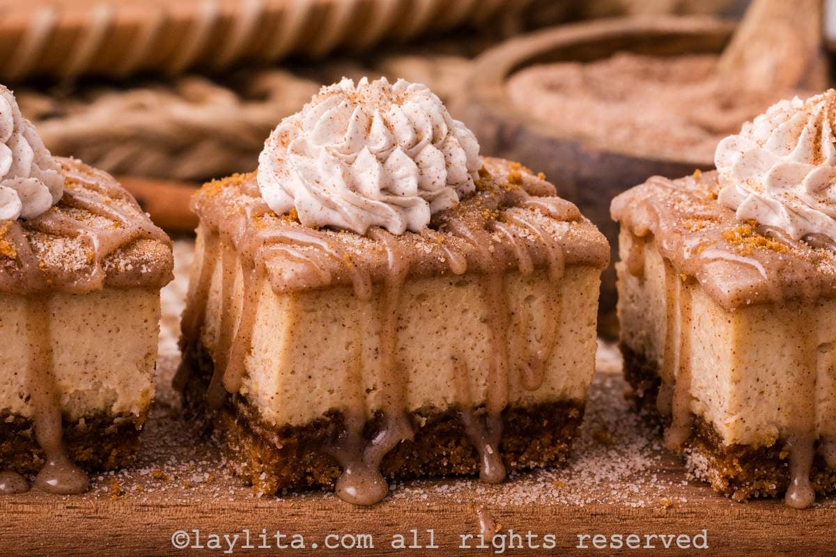 Churro Cheesecake bars topped with cinnamon whipped cream on a wood board