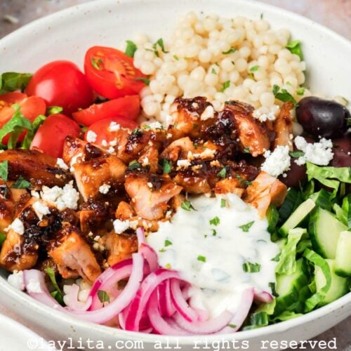 Close up overhead shot of a harissa chicken bowl with veggies and sauce