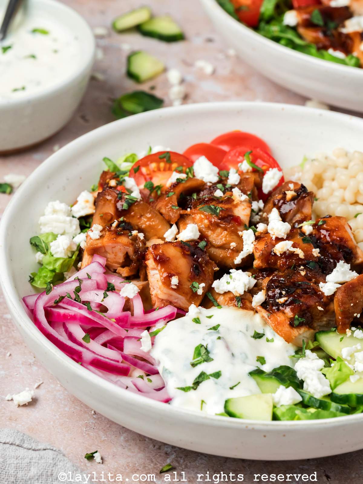Side view of harissa chicken bowl with couscous, vegetables and mint yogurt sauce 