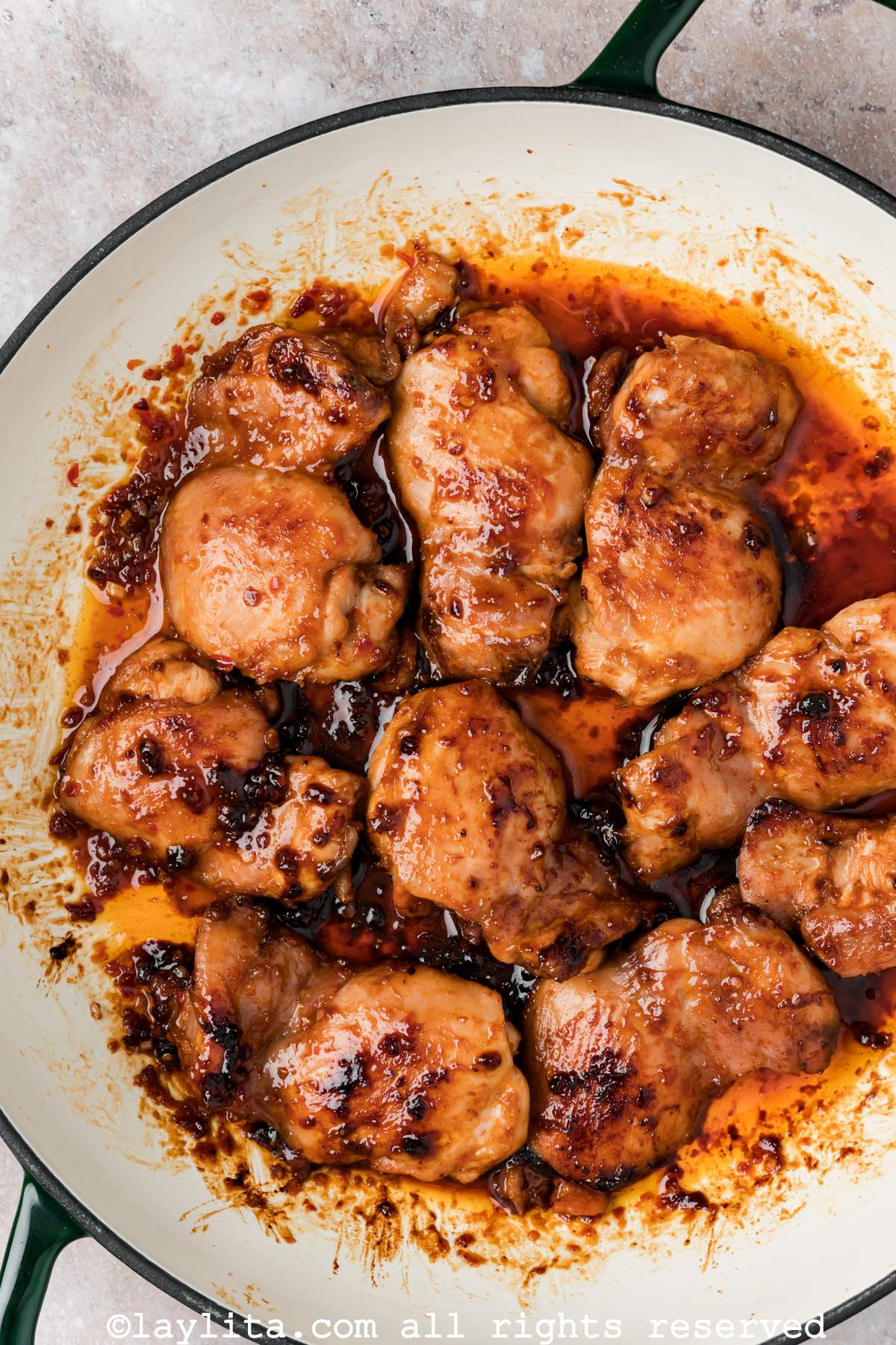 Overhead view of a skillet full of cooked harissa chicken thighs