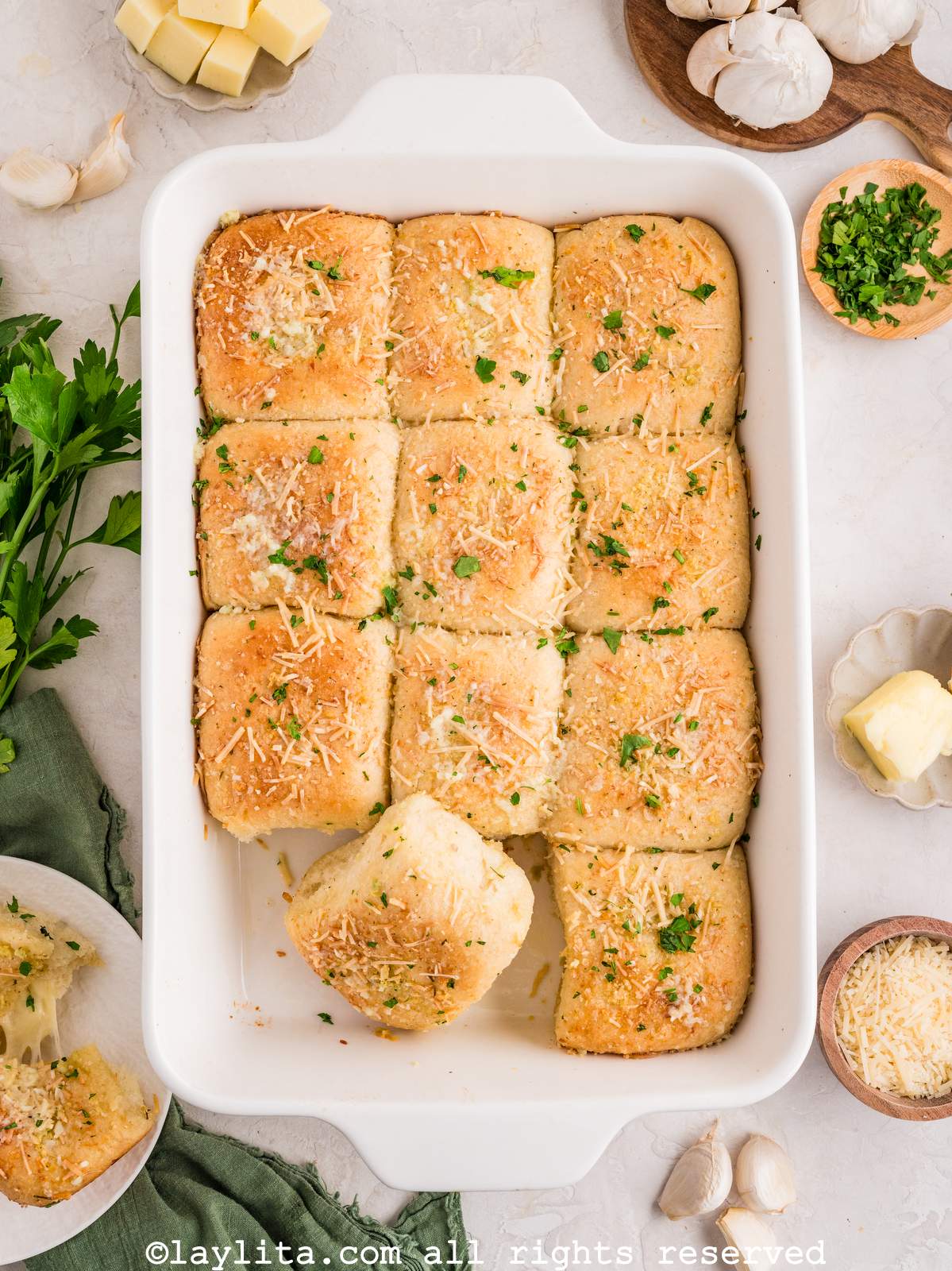 Overhead shot of cheese stuffed dinner rolls in a white baking dish with one roll leaning on the others.