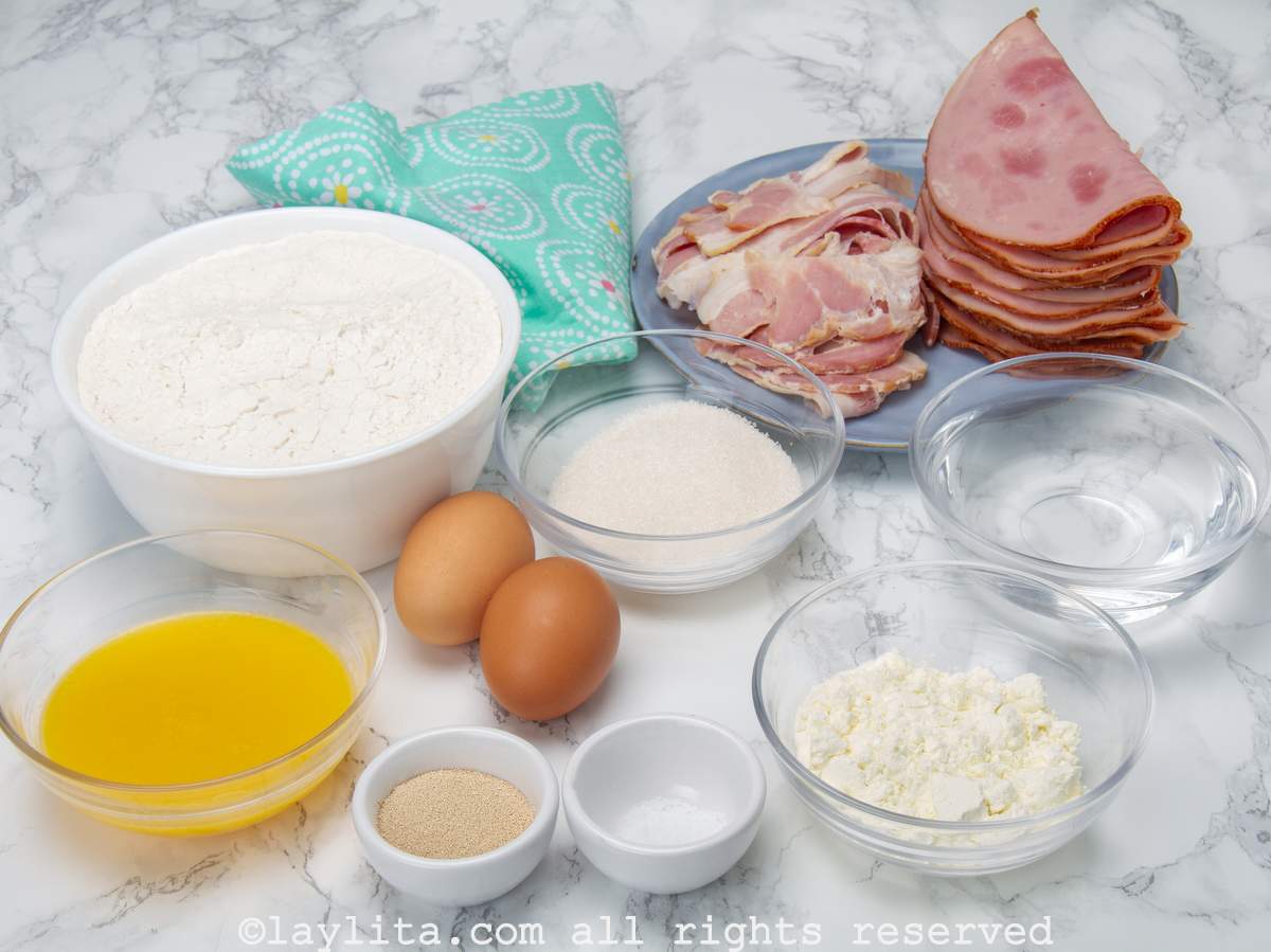 Ingredients needed to make Venezuelan cachitos or ham filled bread rolls on a counter.