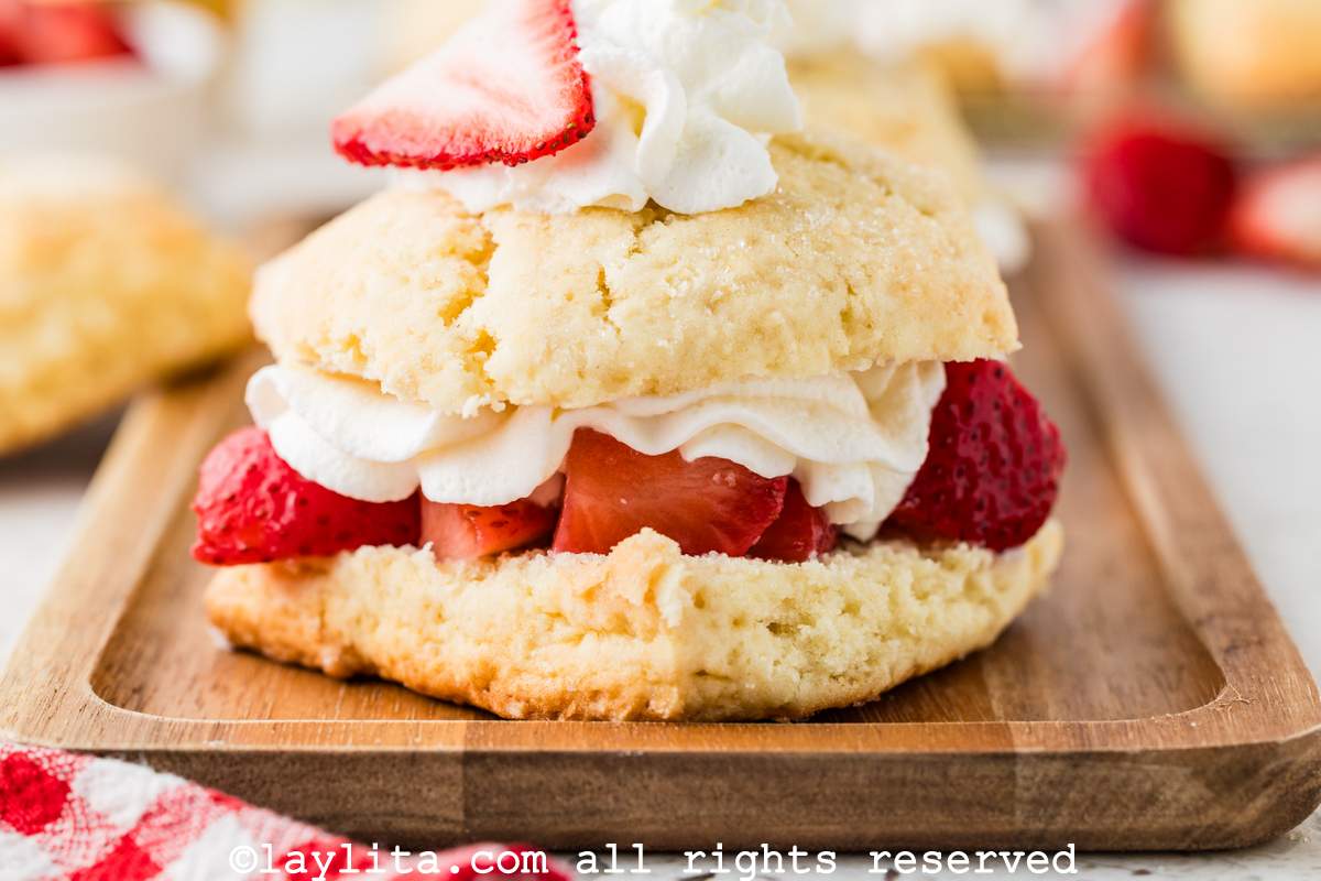 Close up side view of a strawberry shortcake on a wooden board.