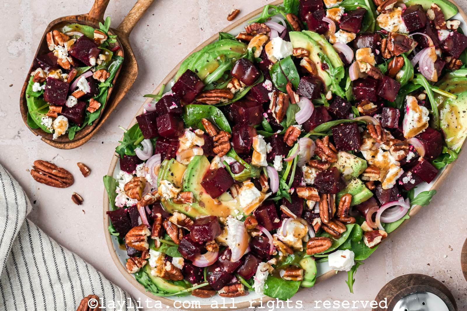 A salad with beets, avocados, pecans and feta cheese on a serving platter