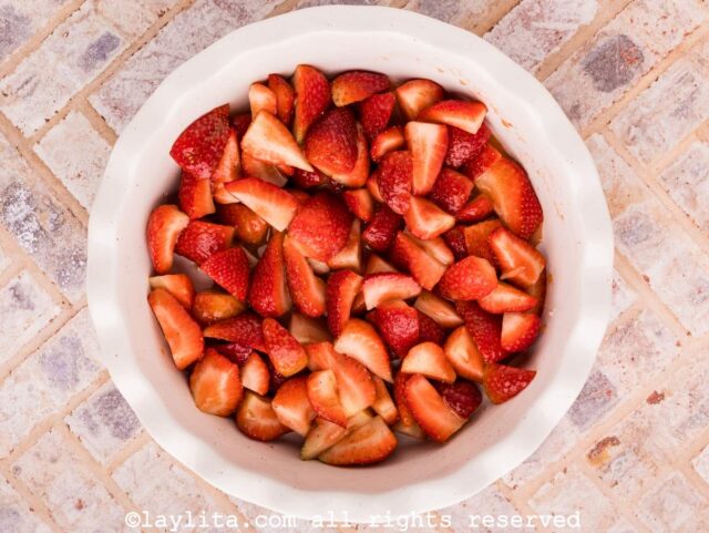 Quartered strawberries in a white pie baking dish