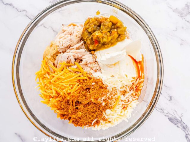 Shredded chicken, cheddar cheese, monterrey jack, cream cheese, and spices in a bowl