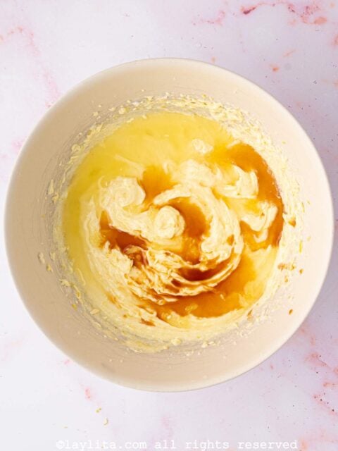 Lemon juice and vanilla extract being added to a cupcake batter in a large bowl