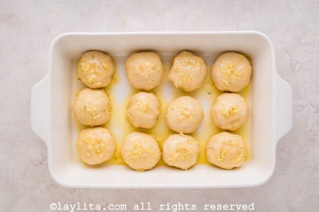 Unbaked dinner rolls in a white baking dish