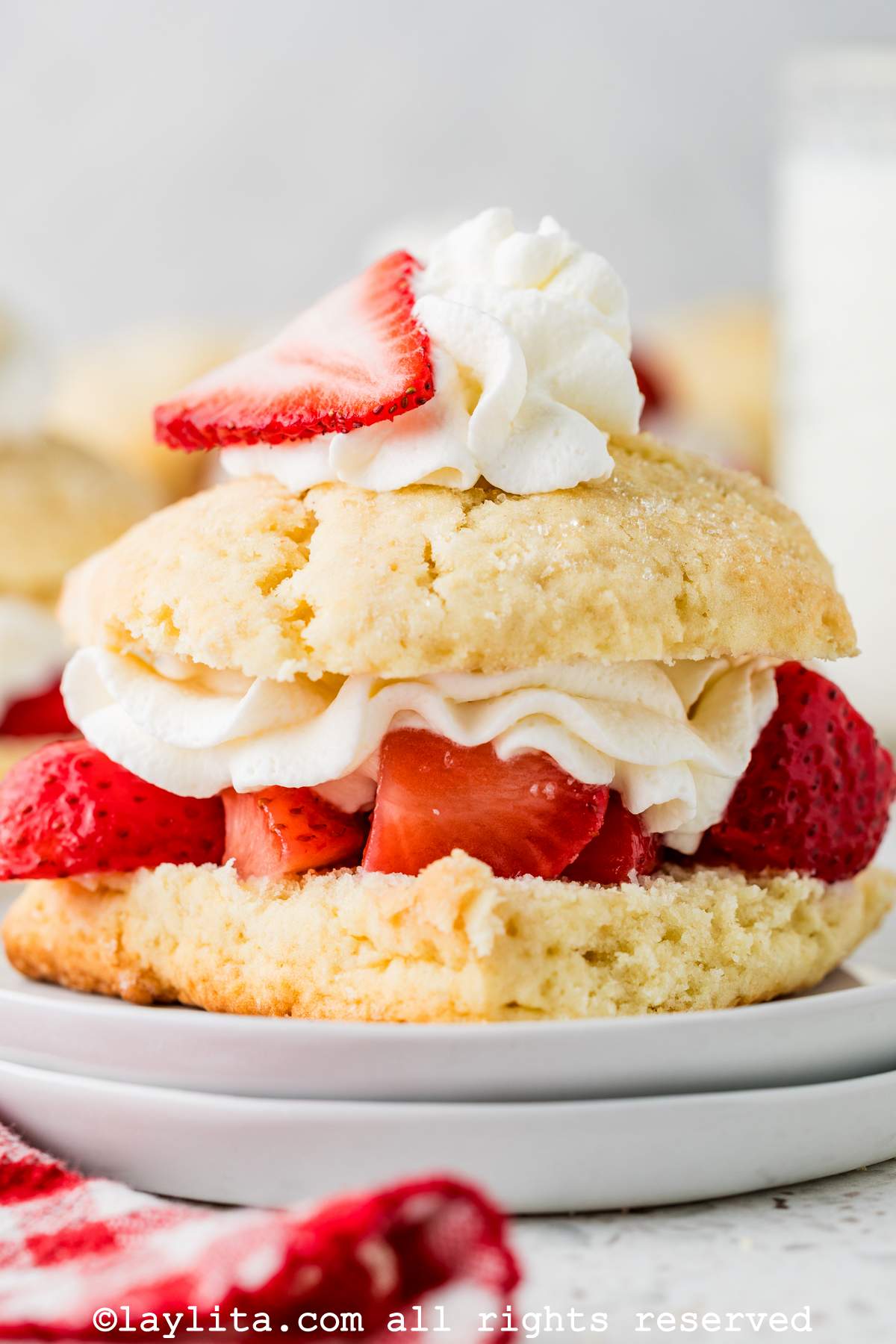 Close up of a shortcake biscuit with strawberries and cream in the middle and on top