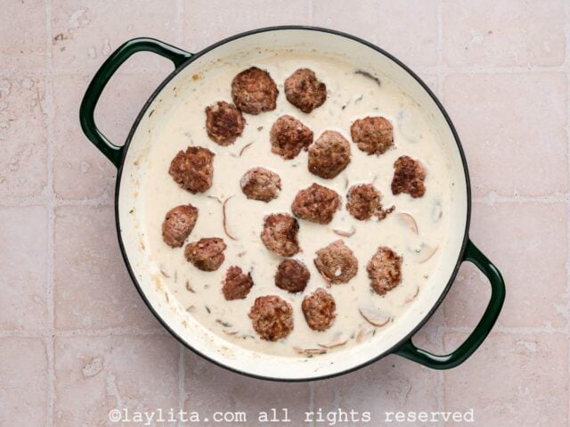 Beef meatballs cooking in creamy stroganoff sauce in a skillet