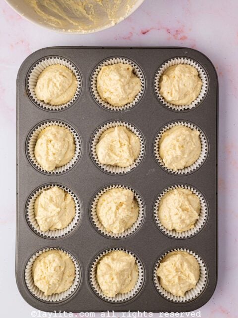 A baking pan with uncooked cupcakes