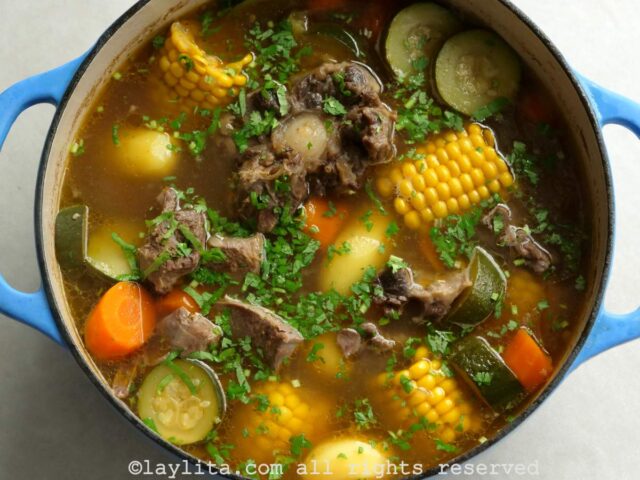 Overhead shot of a large Dutch oven pot of caldo de res with chopped cilantro added on top