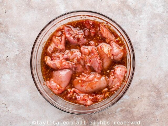 A large bowl full of chicken thighs in a honey harissa marinade