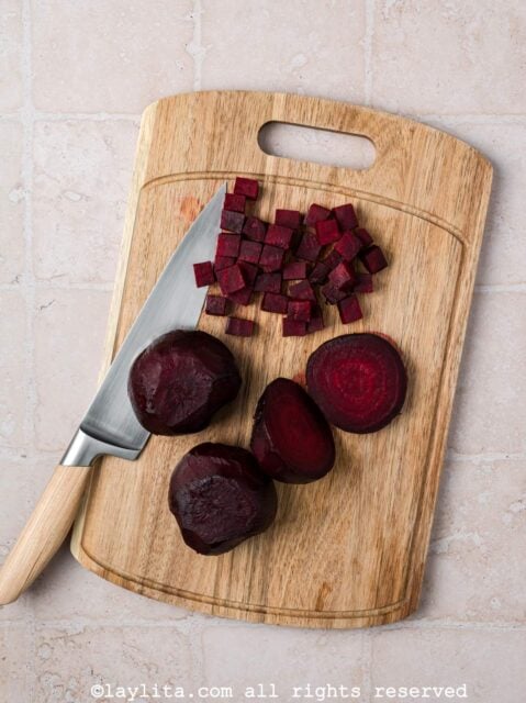 Roasted beets being diced on a cutting board