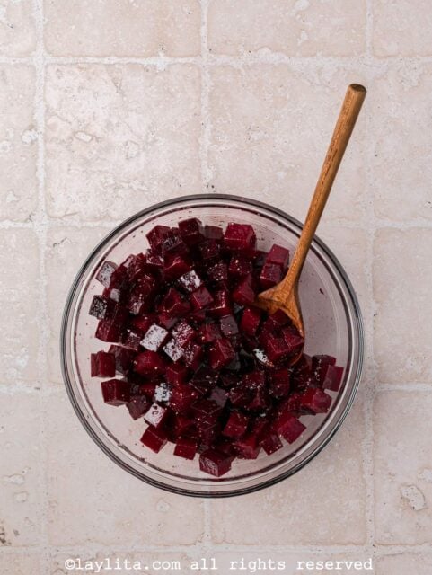 Diced roasted beets with olive oil, salt, pepper in a clear bowl