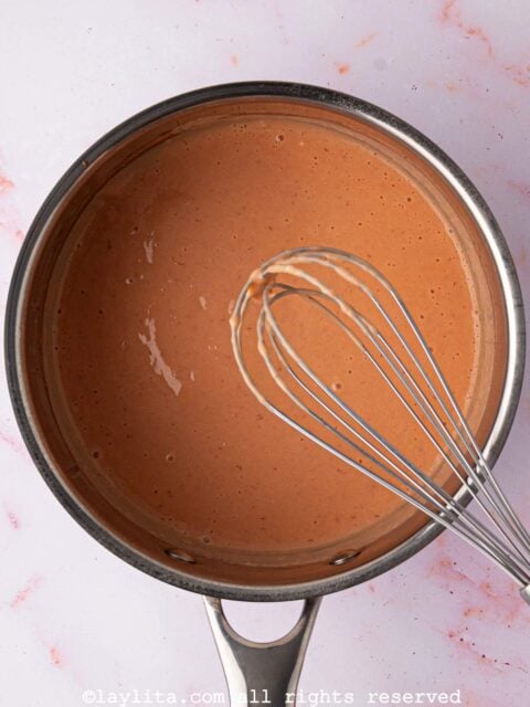 A pot of strawberry lemon curd with a whisk in it