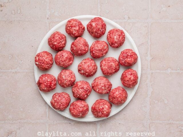 Several raw meatballs on a white plate