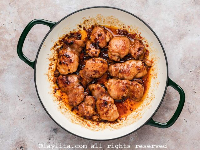 Honey harissa marinated chicken thighs cooking in a skillet