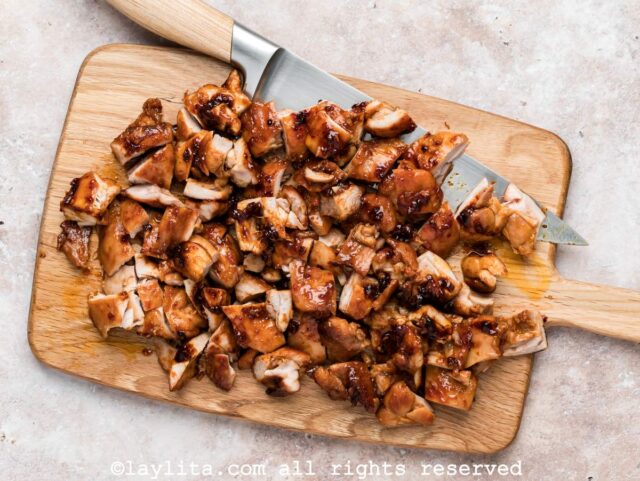 Honey harissa marinated chicken thighs cut into bite sized pieces on a cutting board
