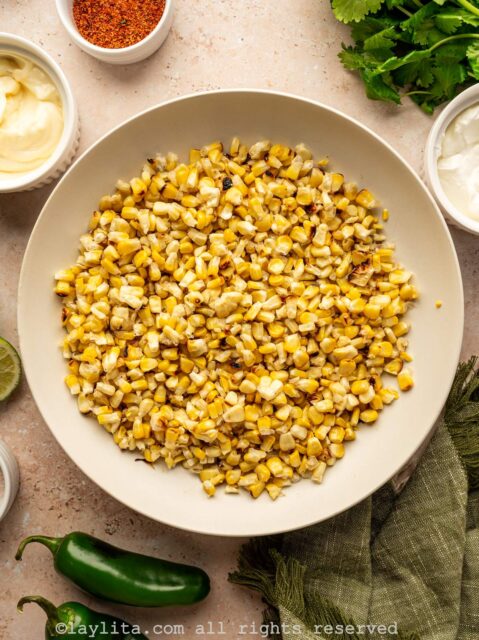 A white bowl full of kernels of grilled corn