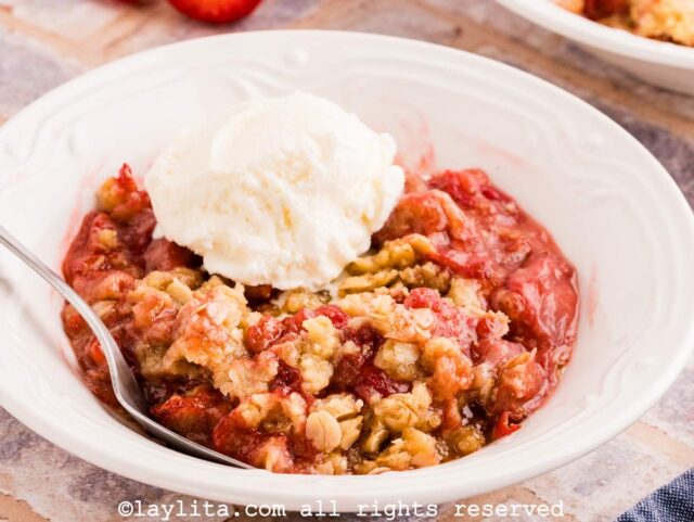 Strawberry crisp with a scoop of vanilla ice cream in a white bowl
