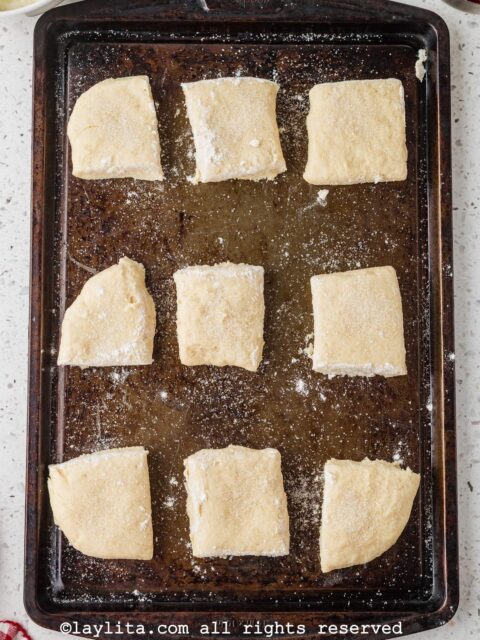 Overhead shot of a baking sheet with several shortcake biscuits before baking