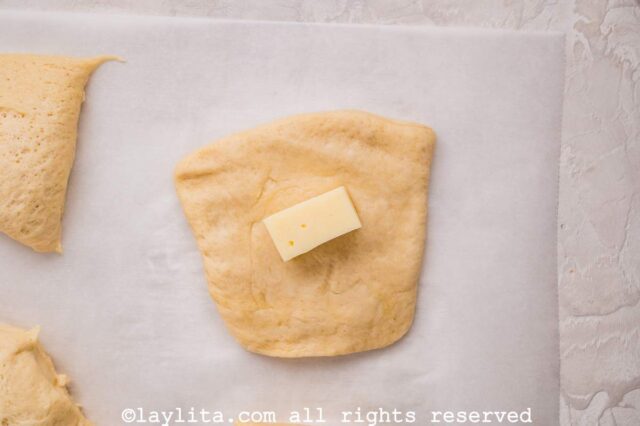 A piece of bread dough with a chunk of cheese in the middle