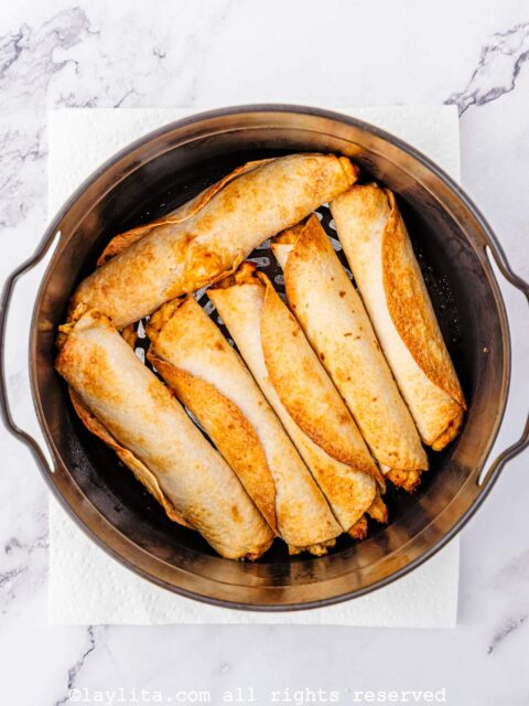 Crispy chicken taquitos in the air fryer basket after cooking