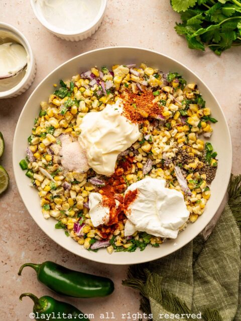 Mayonnaise, sour cream, Tajín, paprika, garlic, lime juice being added to the corn salad