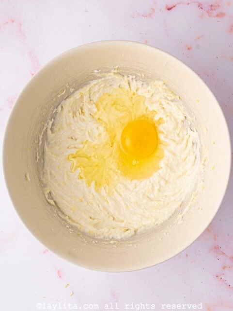 Eggs being added to a batter in a bowl
