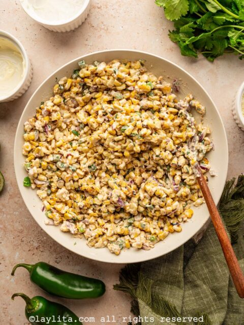 A white bowl with corn salad tossed with a creamy dressing