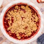 Strawberry Crisp in a white pie dish on a tile countertop with fresh strawberries on the side