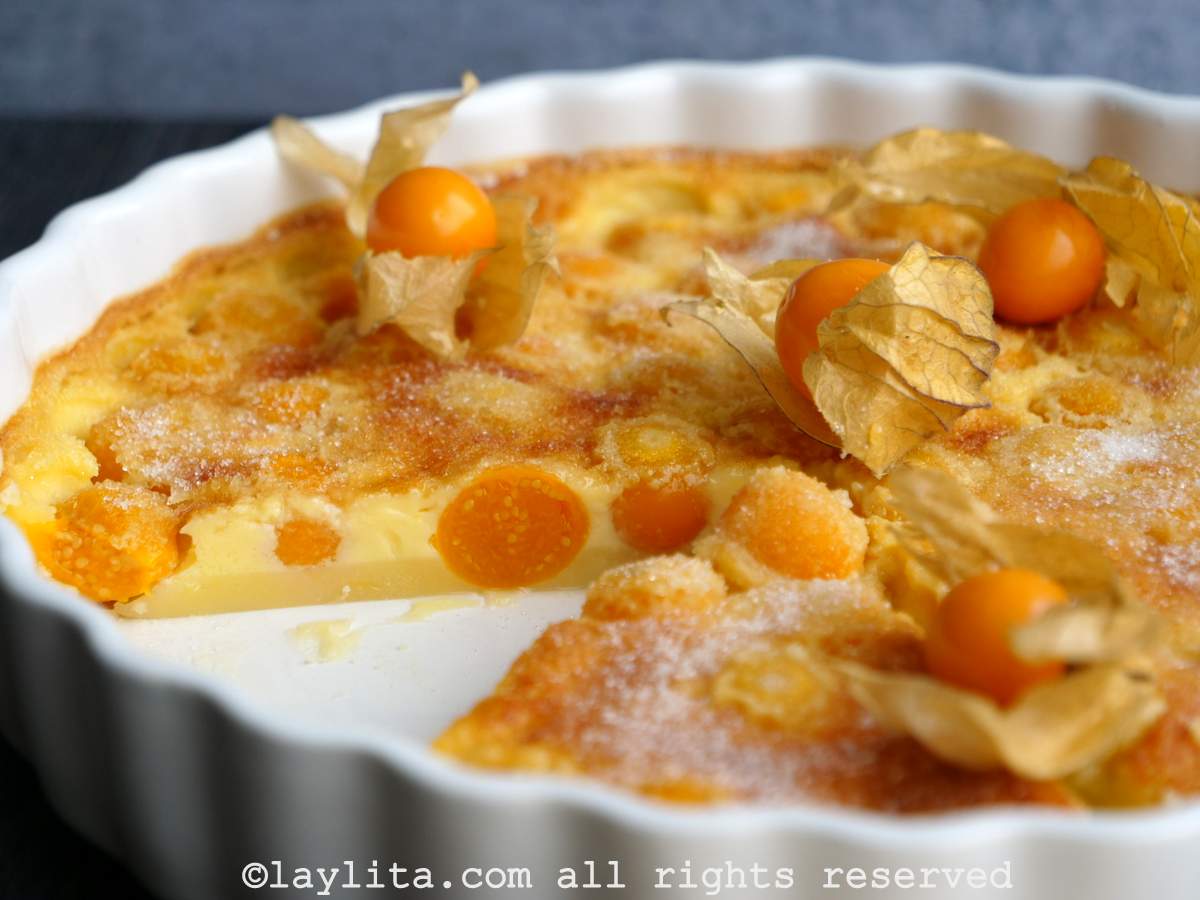 Side view of an uvilla clafoutis in a white tart pan with a slice missing to show the inside.