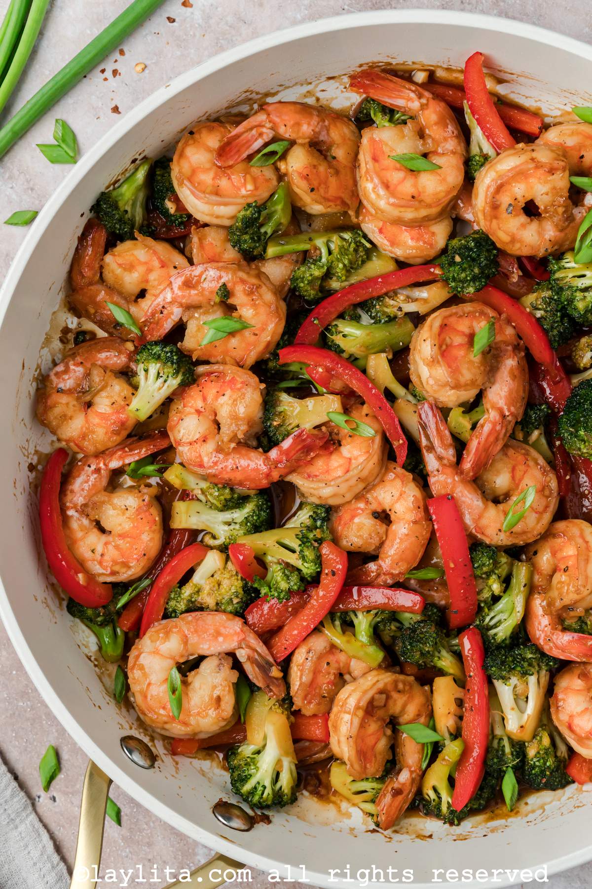 Overhead view of shrimp broccoli stir fry in a white skillet