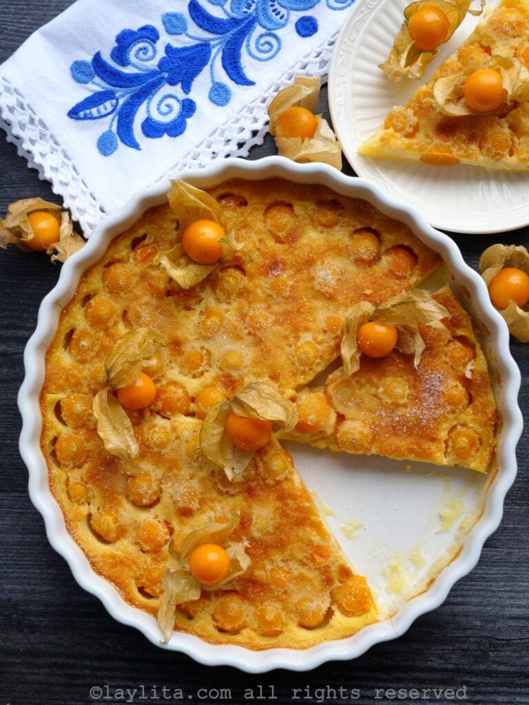 Overhead shot of uvilla clafoutis in a white tart pan with fresh uvillas on top as garnish.